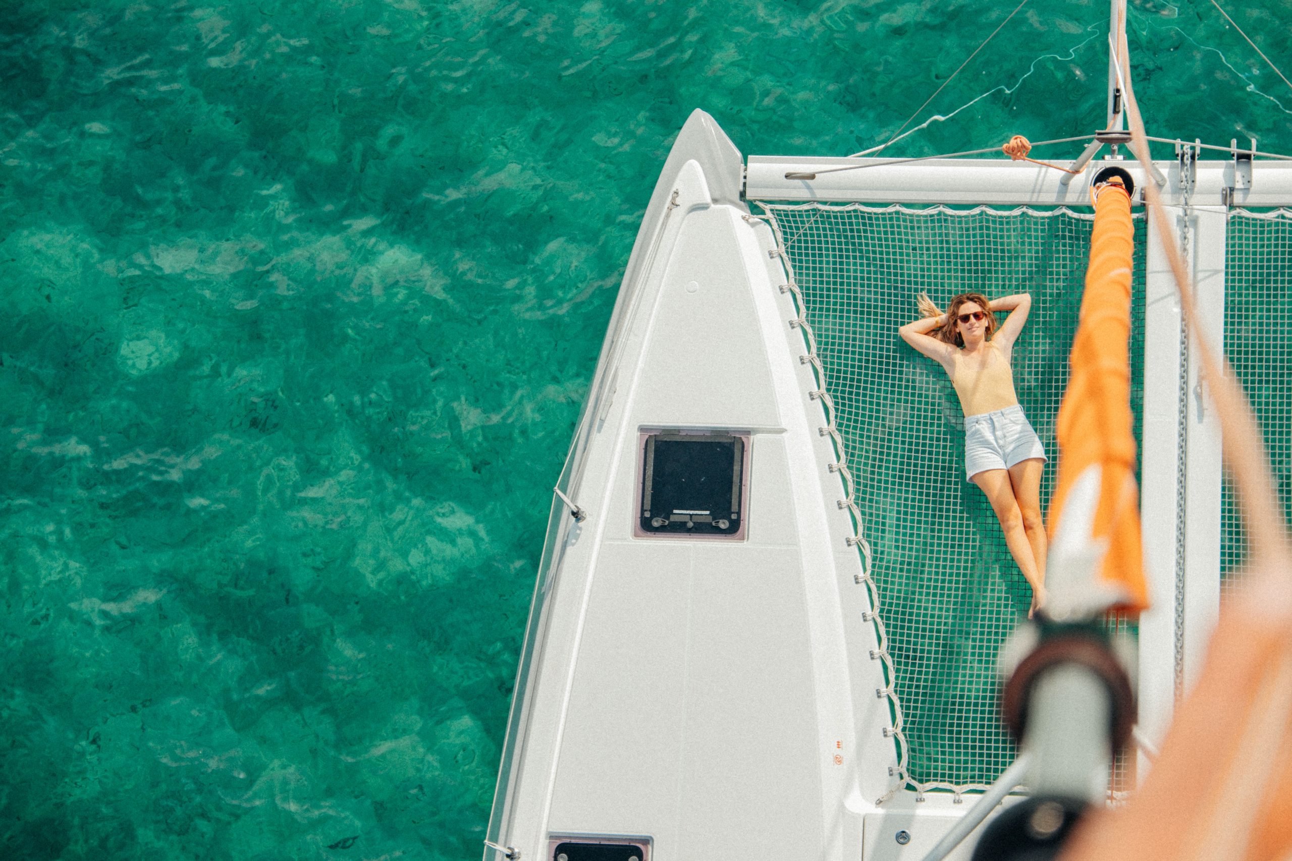 Lounging on the Excess 11 foredeck trampoline over clear water